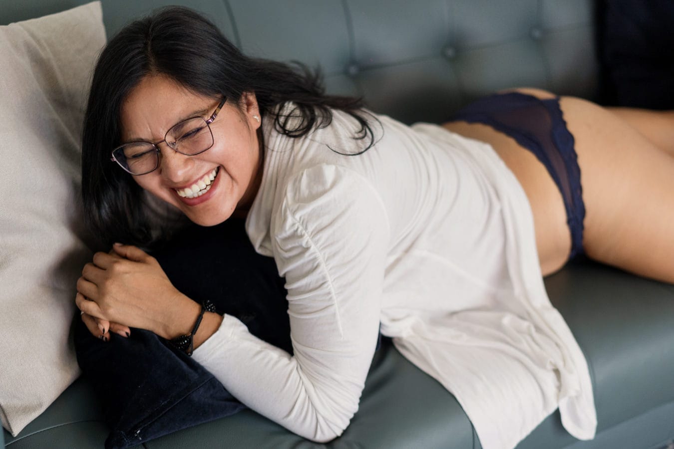 Woman laughing during a relaxed boudoir session — no posing, just conversation